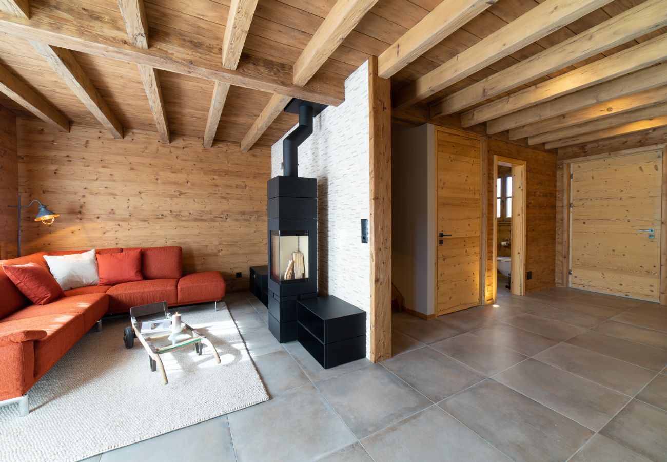 A bright living area with a red sofa, a fireplace, a wooden ceiling and large windows.
