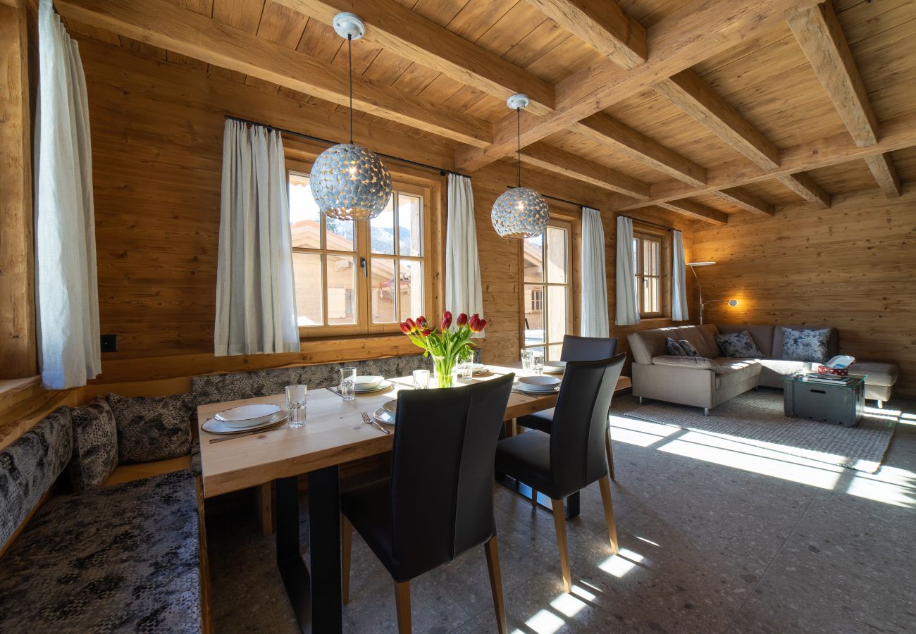 Bright living and dining area in a wooden chalet with dining table, sofa and large windows